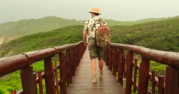 배낭을 여행하는 남자들은 가운데있는 다리를 걷는다 모자와 셔츠를 사파리 스타일의 — 비디오