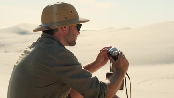 Man Travel Clothes Sits Sand Dune Desert Takes Photo Film — Stok video