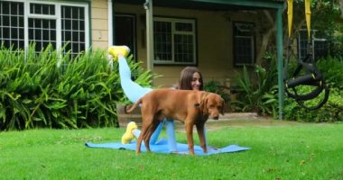 Sports Woman Exercising With Band. Fit female athlete in activewear doing forward lunges exercise with elastic resistance rubber glute band. athletic woman doing exercises on the grass next to the dog