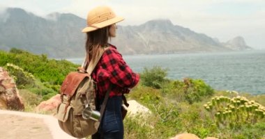 Okyanus kıyısındaki dağlarda yürüyüş yapan arkadaşlar Norveç 'te macera dolu açık hava yaz tatillerinde seyahat ediyorlar. Turist şapkalı şık bir kız gezgin okyanusa bakıyor, manzaranın tadını çıkarıyor..