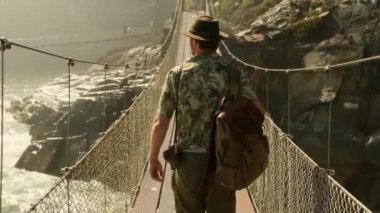 Tatil konseptinde mutlu gezginler. Komik gezgin yolculuğunun tadını çıkar ve maceraya hazır ol. Norveç 'in İskandinav manzarası üzerinde tahta bir köprüden geçen kayalık yolda bir turist yürüyüşçüsü..