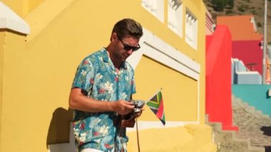 Muslim Malay village, popular landmark in Cape Town. a beautiful male tourist in a summer dress with the flag of south africa stands near colorful houses in cape town taking a selfie