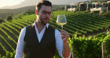 wine bottle and glass on wodden barrel. on a wooden table there is a bottle of wine and a glass of red wine at sunset, a man shows a heart of hands. sommelier waiting for his new vintage of grapes