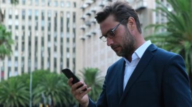 Stressed dissatisfied American businessman reading letter with bad news, unexpected debt, bank or job dismiss notification. american businessman in suit on wall street reading bad news on phone