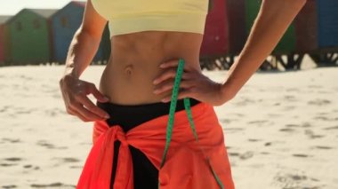 A body centimeter in the hands of girl in tracksuit after a workout or fitness session. Measurement of body volume. Sports waist. The girls healthy athletic body, diet, weight loss, calorie count.