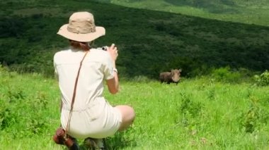 a male traveler takes a photo on a film camera of a wild boarin the savannah. giraffe in the savannah Serengeti National Park at sunset. Wild nature of Tanzania - Africa. Safari Travel Destination.