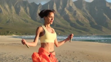 sporty woman skipping rope. stylish athletic woman goes in for sports on a wild beach at sunset. Sexy athletic woman rope jumping exercises outdoors on beach. Healthy lifestyle. morning workout