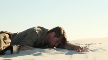 Exhausted man in the desert. Apathy, fatigue, exhaustion, mental disorders concept. Mental health. an unconscious man lies on the sand in the desert, dies without water from thirst