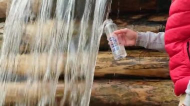 a man quenches his thirst on a hike in the forest from a mountain river. wave water surface with bubbles. a mans hand draws clean cold water from a mountain waterfall into a tourist bottle.