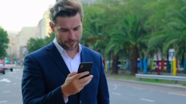 middle-aged man browsing internet reading news. man in glasses typing sms. Happy relaxed man holding his mobile phone. stylish man in a business suit wearing glasses. stylish man in sunglasses
