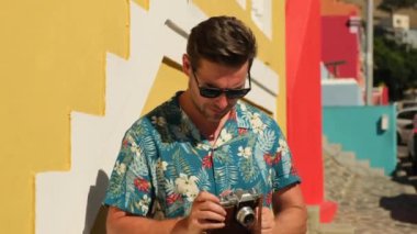 Young man photographer takes photographs with camera in a city. Travel, vacations, professional freelance work and active lifestyle concept. stylish man with a film camera takes a photo