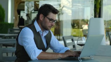 Coworking and freelance concept. male in a white shirt sits with a laptop and a glass of wine. Businessman using laptop and smartphone in the office, entrepreneur, freelance worker, business
