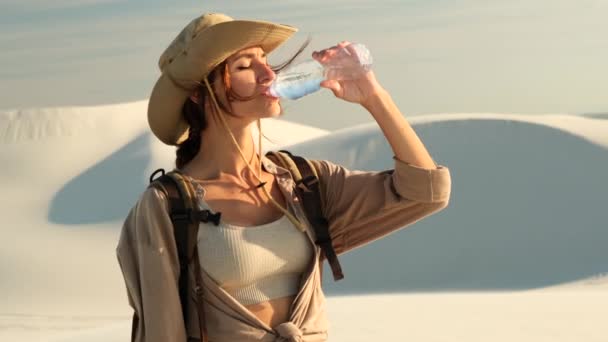 長いストレートの髪をした若い美少女魔法瓶から飲んでる トレッキングの概念 暑い砂漠を旅する女性は太陽の下で水を飲むと喉が渇く — ストック動画