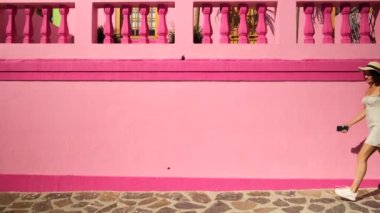 Beyaz elbiseli kadın sokakta dans ediyor. Yazlık elbiseli neşeli Afrikalı kız geri dönüyor. Elbiseli şık bir gezgin Güney Afrika bayrağını taşıyor ve renkli evlerin yanında eğleniyor.