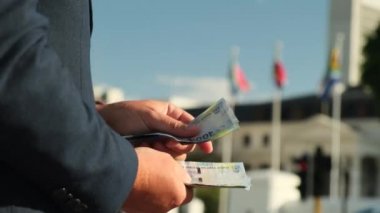 Adam Güney Afrika 'nın paralarını sayıyor. Güney Afrika bayrağının arka planında beyaz gömlek ve takım elbiseli Avrupalı bir işadamının ellerine yakın plan çekilmiş.