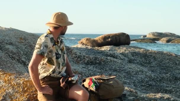 Αρσενικό Ταξιδιώτη Ένα Καπέλο Σαφάρι Κατασκήνωσε Και Στηρίζεται Μια Πέτρα — Αρχείο Βίντεο