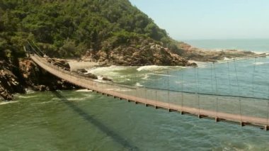 Güney Afrika 'daki Tsitsikama Ulusal Parkı. Ulusal parktaki donanımlı bir turist ekolojik gezisinde asma köprü. Tsitsikama Milli Parkı 'ndaki kayalık yamaçlarda kıyı ve yağmur ormanları.