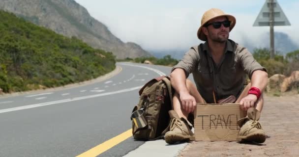 Człowiek Siedzący Poboczu Tabliczką Przyjedź Mnie Mężczyzna Stojący Autostopem Poboczu — Wideo stockowe
