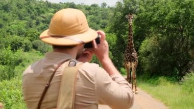 Erkek fotoğrafçı, turistik araçtan profesyonel kamerayla tropikal safaride fotoğraf çekiyor. Baharda gün doğumunda doğa fotoğrafçısı. Fotoğraf çeken.