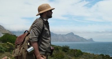 Güneş şapkalı erkek gezgin okyanusta duruyor. Kvalvika sahilinde oturan adam okyanus manzaralı seyahatlerin tadını çıkarıyor. Norveç 'te turizm turizmi gezisi sağlıklı bir yaz gezisi..