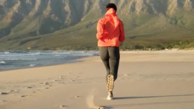 Doğada antrenman, kardiyo, atletik yaşam tarzı. Spor konsepti. Açık hava antrenmanı sırasında koşucu fitness koşucusu. Spor ayakkabılı atletik bacaklar kumsalda ve deniz kenarında koşuyor.