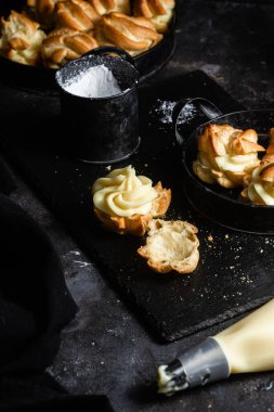 Karanlık bir masada kremalı profiterol. Eklemeler