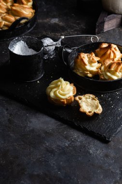 Karanlık bir masada kremalı profiterol. Eklemeler