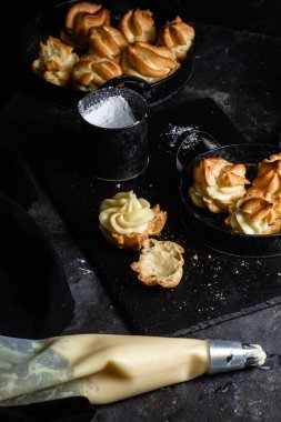 Karanlık bir masada kremalı profiterol. Eklemeler