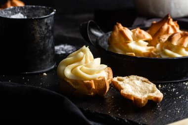 Karanlık bir masada kremalı profiterol. Eklemeler