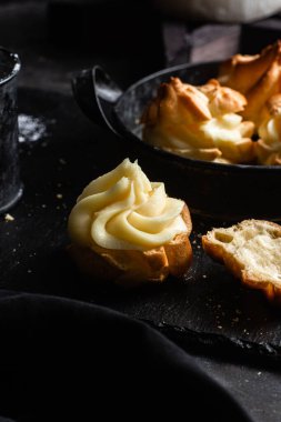 Karanlık bir masada kremalı profiterol. Eklemeler