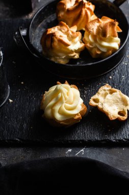 Karanlık bir masada kremalı profiterol. Eklemeler