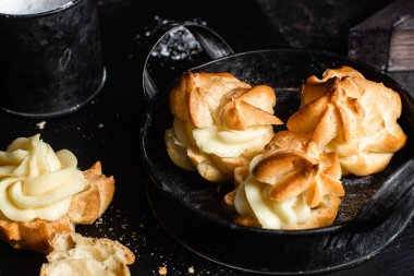 Karanlık bir masada kremalı profiterol. Eklemeler