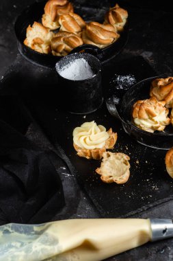 Karanlık bir masada kremalı profiterol. Eklemeler
