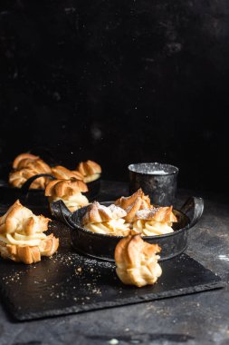 Karanlık bir masada kremalı profiterol. Eklemeler