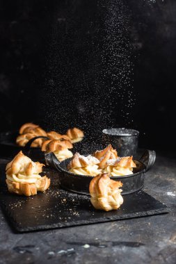 Karanlık bir masada kremalı profiterol. Eklemeler
