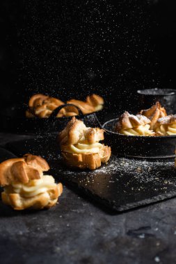 Karanlık bir masada kremalı profiterol. Eklemeler