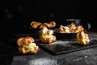 Karanlık bir masada kremalı profiterol. Eklemeler