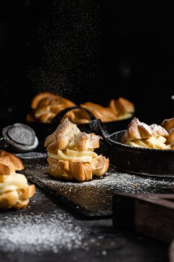 Karanlık bir masada kremalı profiterol. Eklemeler