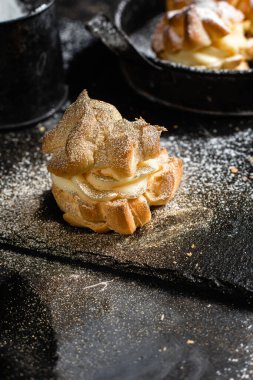 Karanlık bir masada kremalı profiterol. Eklemeler