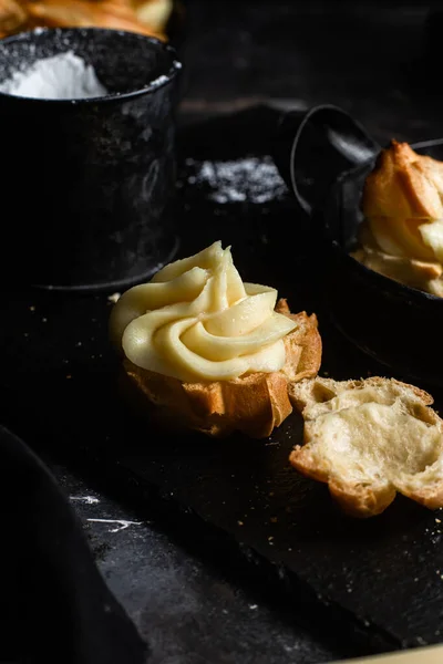 Karanlık bir masada kremalı profiterol. Eklemeler