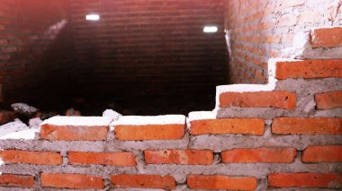 Geleneksel olmayan inşaat alanı. Duvarcılık ihmal edilmiş, sorumsuz, ilerlemeyen, sadece yarısı bitmiş. Bazı kısımlarında duvarların pürüzlü yüzeyleri vardı..