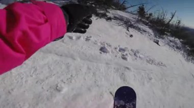 Karlı bir yamaçtan snowboard sporu yapan biri. Snowboardcu bir dağa biniyor..