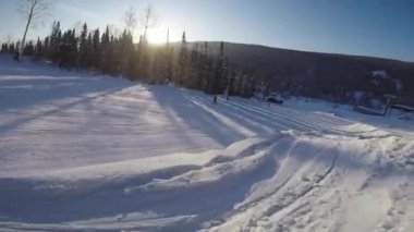 Karlı bir yamaçtan snowboard sporu yapan biri. Snowboardcu bir dağa biniyor..