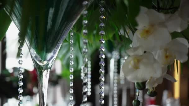 Цветочные украшения на свадьбе. Цветы белых орхидей в вазах на столе — стоковое видео