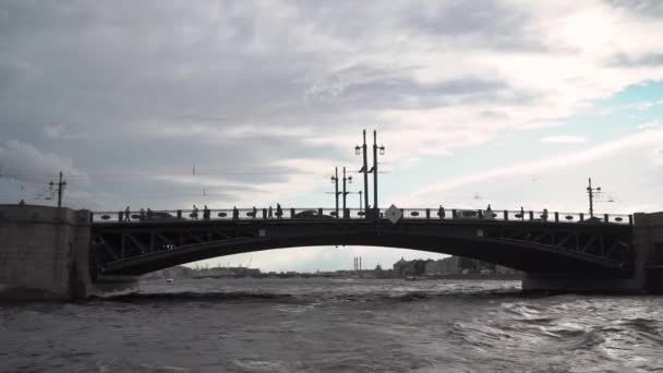 Σιλουέτα γέφυρας στην πόλη απέναντι από το ποτάμι. Πλεύση με πλοίο ή γιοτ κάτω από γέφυρα — Αρχείο Βίντεο