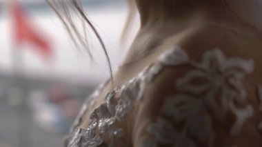 Dantel kollu esmer gelin panoramik bir pencerede duruyor..