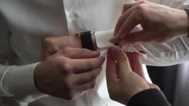 Adam beyaz gömlek giyip kol düğmeleri takıyor, kol düğmeleri takıyor..