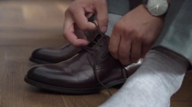 Adam ayakkabılarını giyer. Gri takım elbiseli bir erkek ve çizmelerinde çoraplar var..