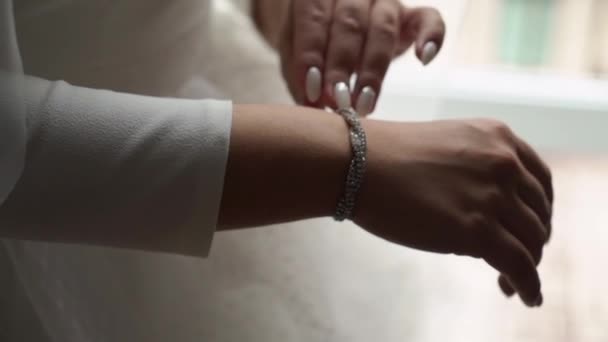 Μια νεαρή γυναίκα βάζει ένα βραχιόλι στο χέρι της. Νυφικά φορέματα την ημέρα του γάμου. — Αρχείο Βίντεο