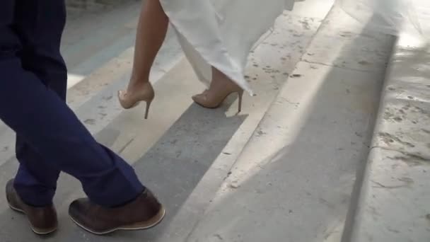 Bride and groom are walking down stairs. Wedding couple is holding hands. — Stock Video